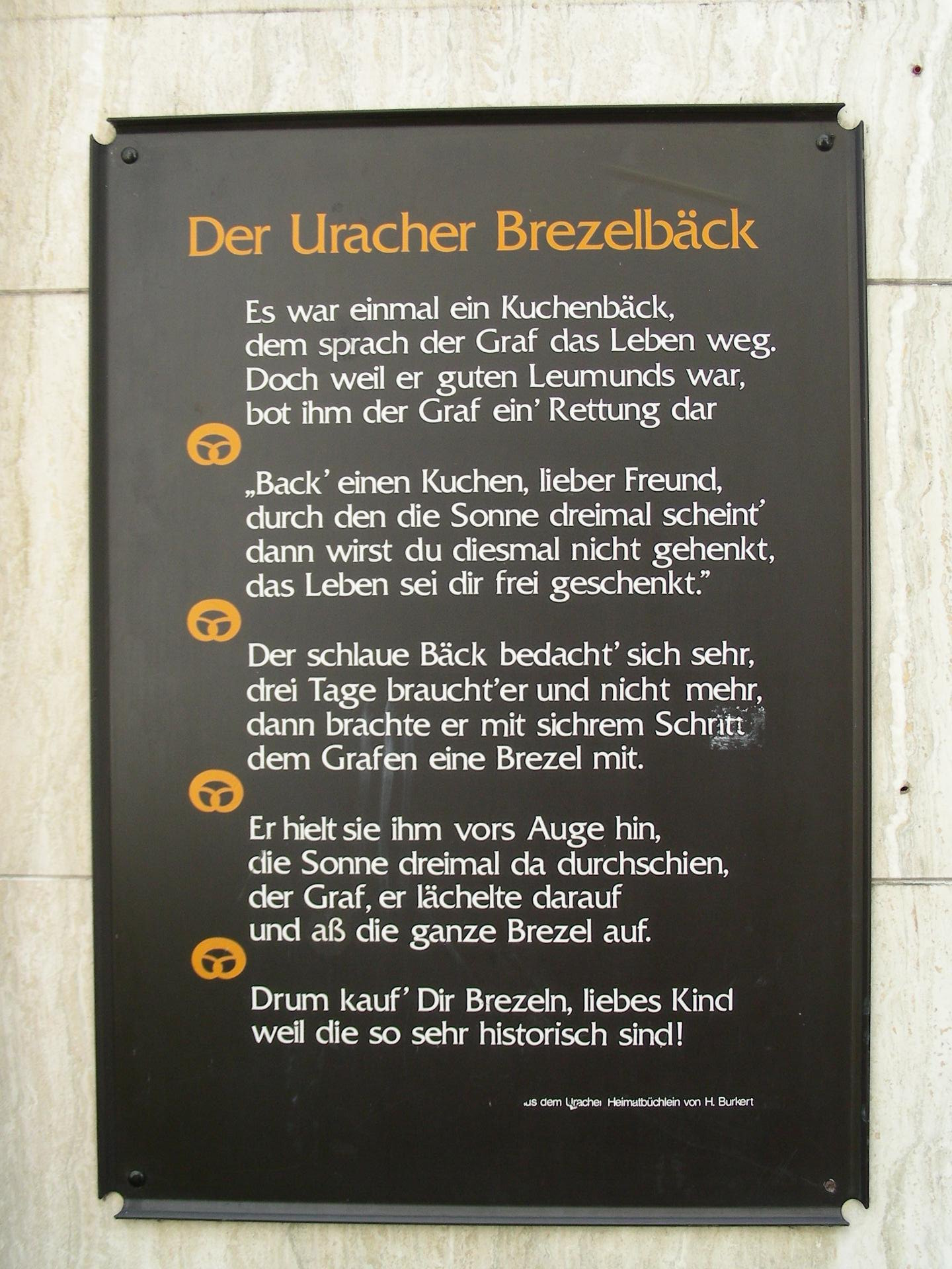 Tafel zur Erfindung der Brezel an einer Bad Uracher Bäckerei in der Nähe des 
								Residenzschloss des Grafen Eberhard V.